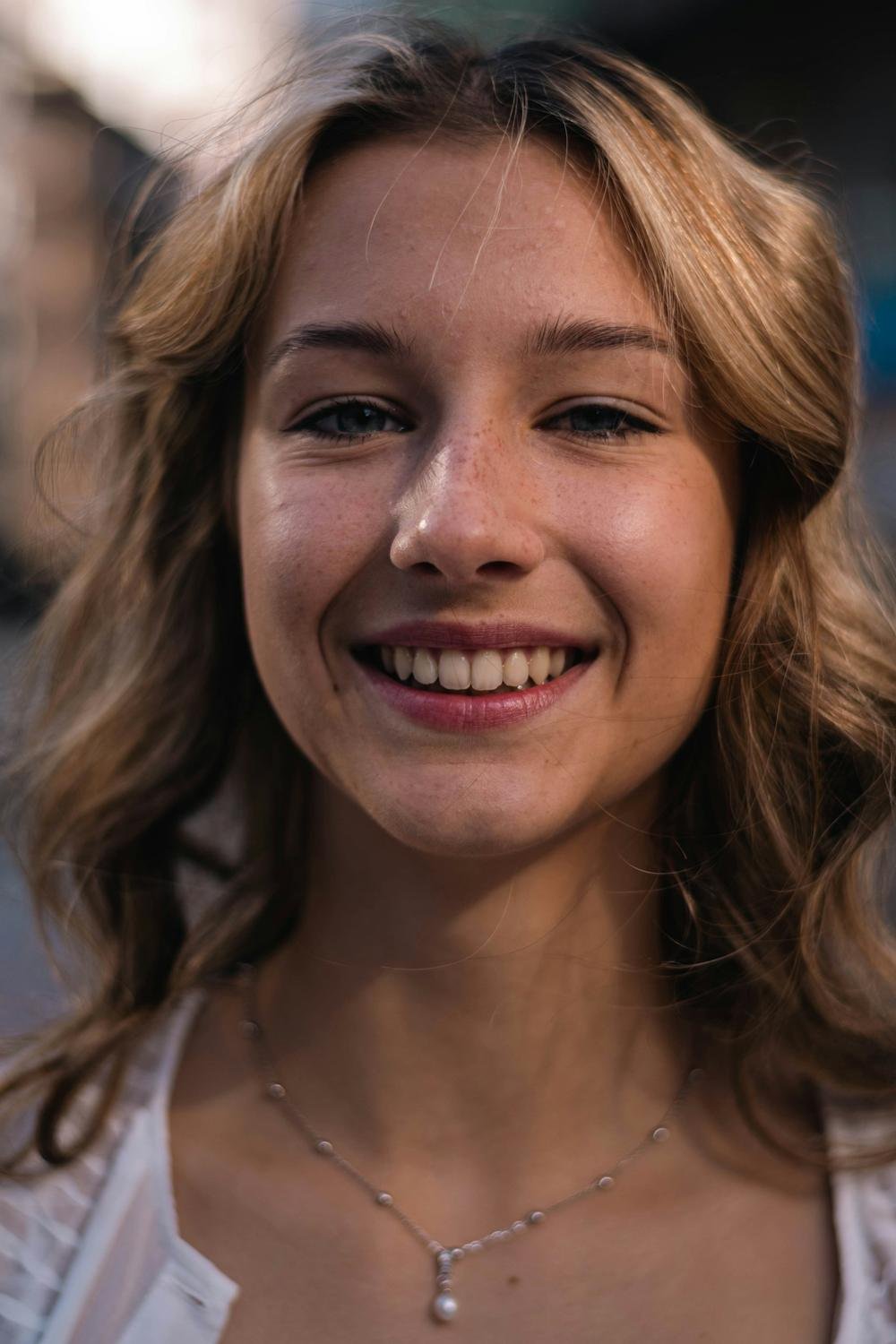 Mulher sorrindo, de frente, com cabelo ondulado
