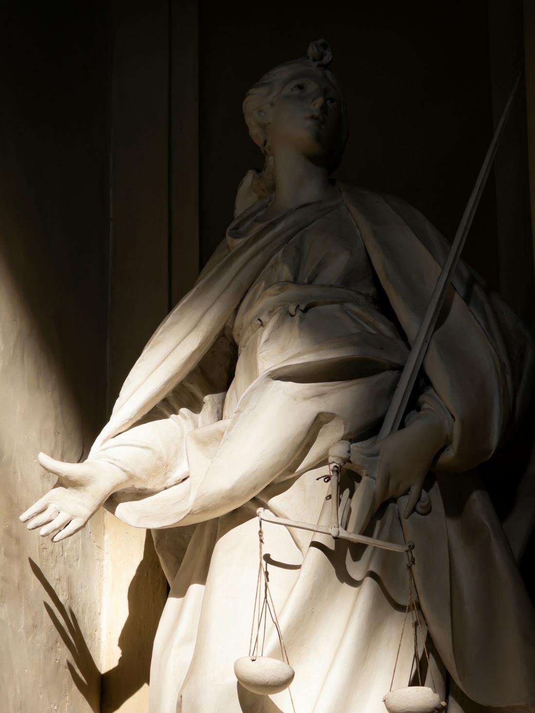 Estátua da Justiça em mármore, com espada e balança